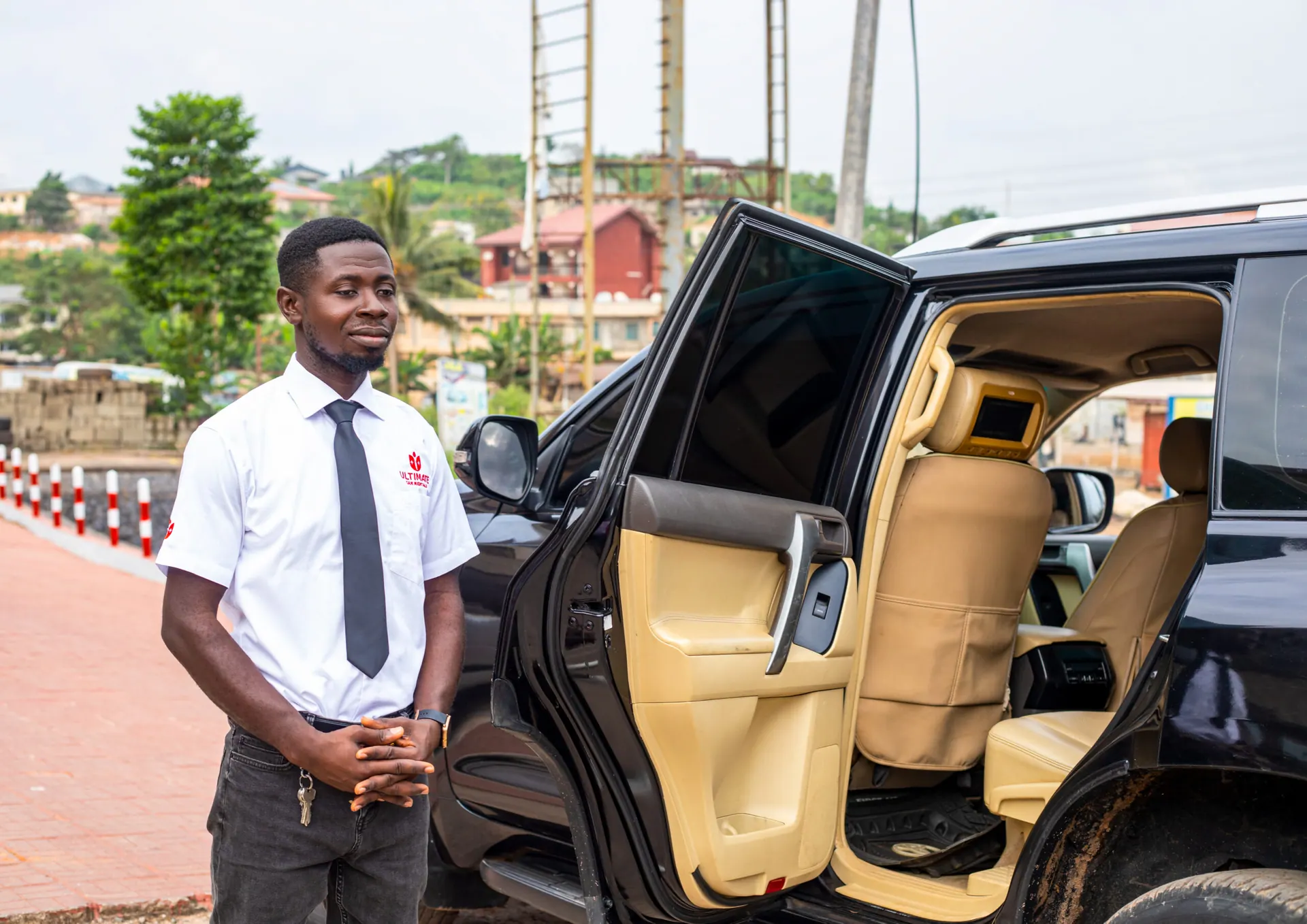 Professional chauffeur standing beside a Toyota Land Cruiser Prado with its door open