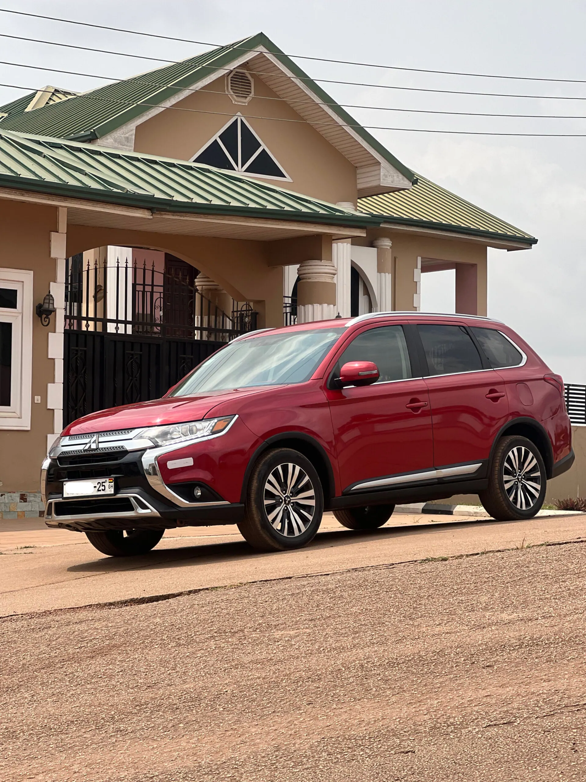 Wine Mitsubishi Outlander parked in front of a house